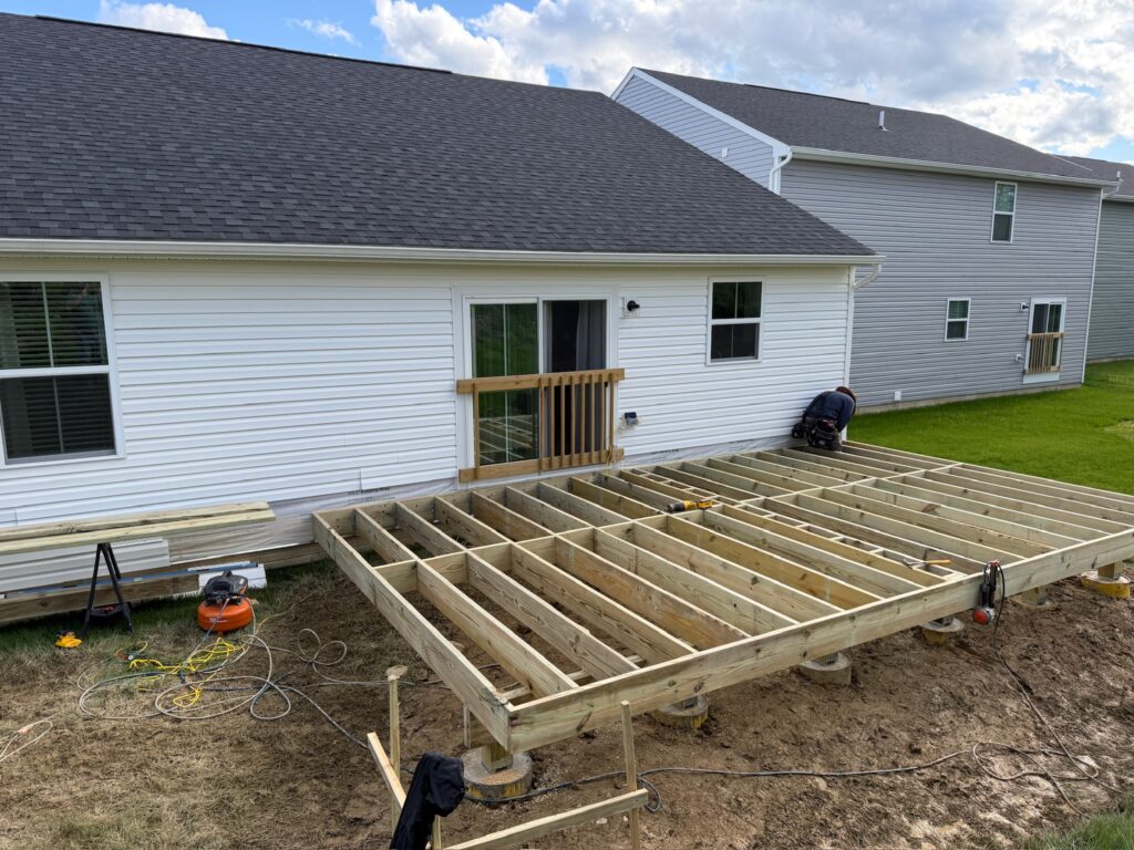 Deck framing installation in progress for a custom outdoor living space in Medina, Ohio featuring pressure-treated lumber and structural framing by BJK Construction.